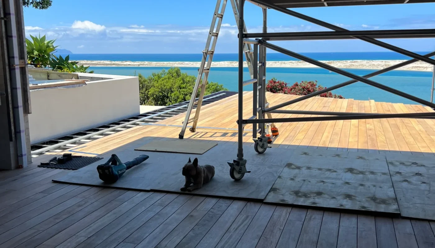 Outdoor deck under construction with scaffolding and stunning ocean backdrop, expertly built by Brock Cooley Builders